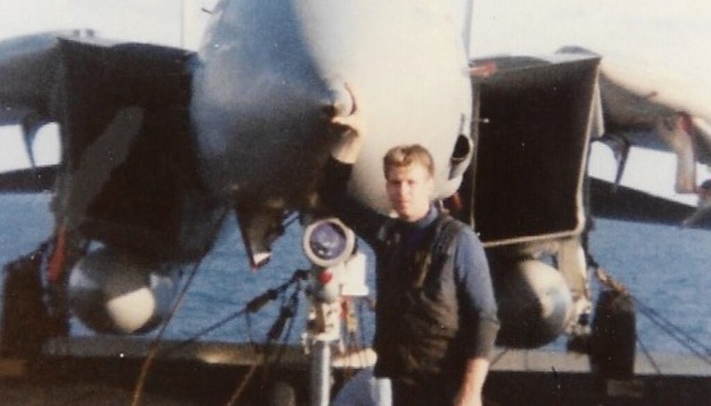 Petty Officer Jim McCune standing by an F-14 aboard USS KITTY HAWK