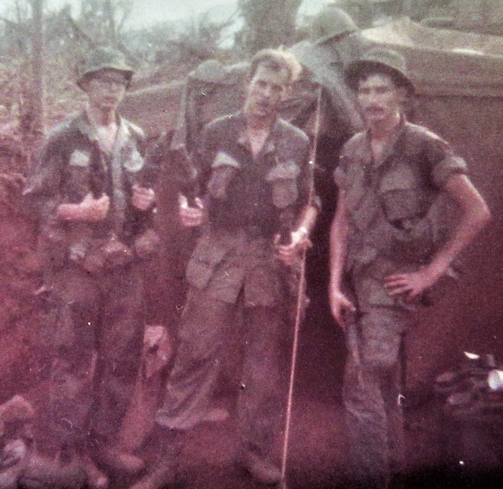 Dave Anson with two other soldiers holding captured weapons.