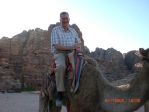 Photo of Dave Grogan riding a camel in Petra, Jordan