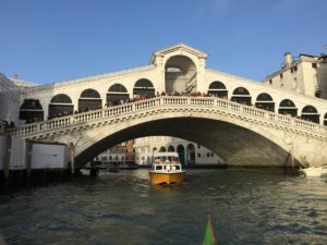 Photo of Rialto Bridge in Venice, Italy, with a water taxi passing under