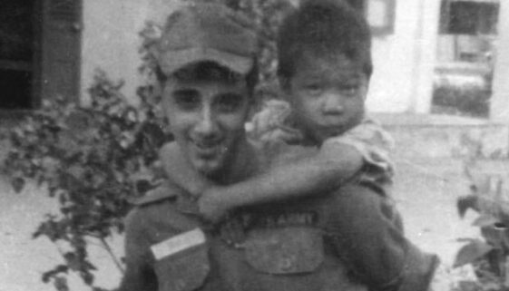 Specialist Billy Terrell at Mang Lang Orphanage with a boy on his back