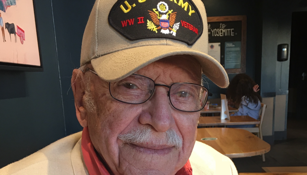 A World War II veteran wearing a World War II veteran baseball cap