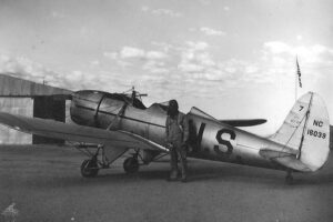 Pilot trainee standing next to a World War II Navy training aircraft