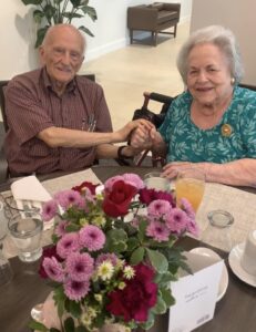 A man and his wife at a table with a beautiful flower arrangement