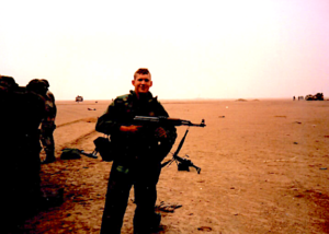 U.S. soldier holding an automatic weapon in the Iraqi desert.