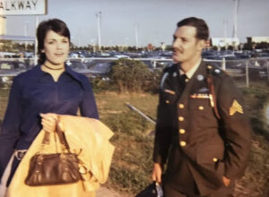 Woman holding coat with man in Army uniform nearby