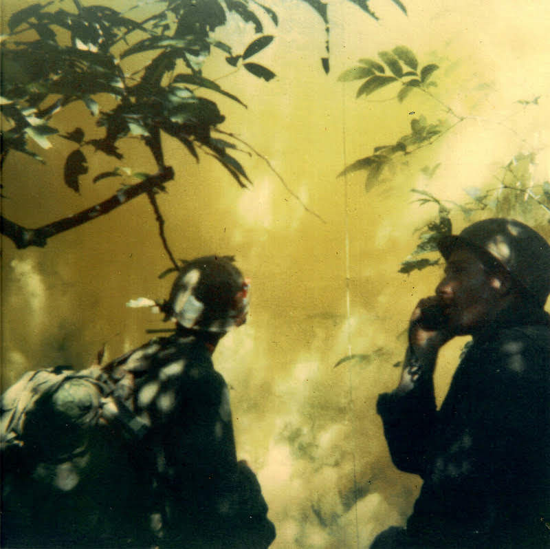 Two soldiers on patrol in the jungle with yellow light shining all around