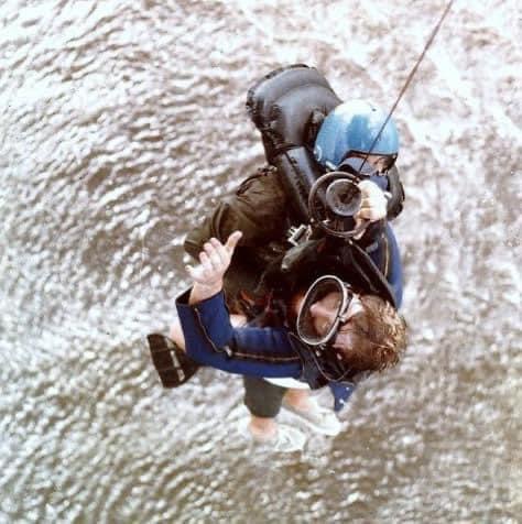 Navy rescue swimmer and pilot being hoisted into a helicopter above a river