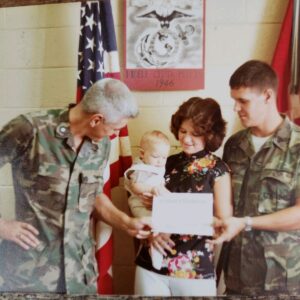 An enlisted Marine with his wife and baby son being reenlisted by a Marine Corps officer