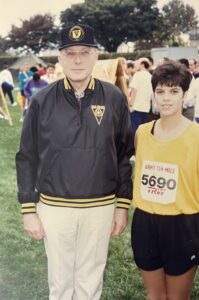 Senior male army officer in civilian clothes standing next to female army officer in PT gear after running a race