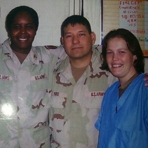 Two male soldiers in uniform with a female soldier in hospital scrubs