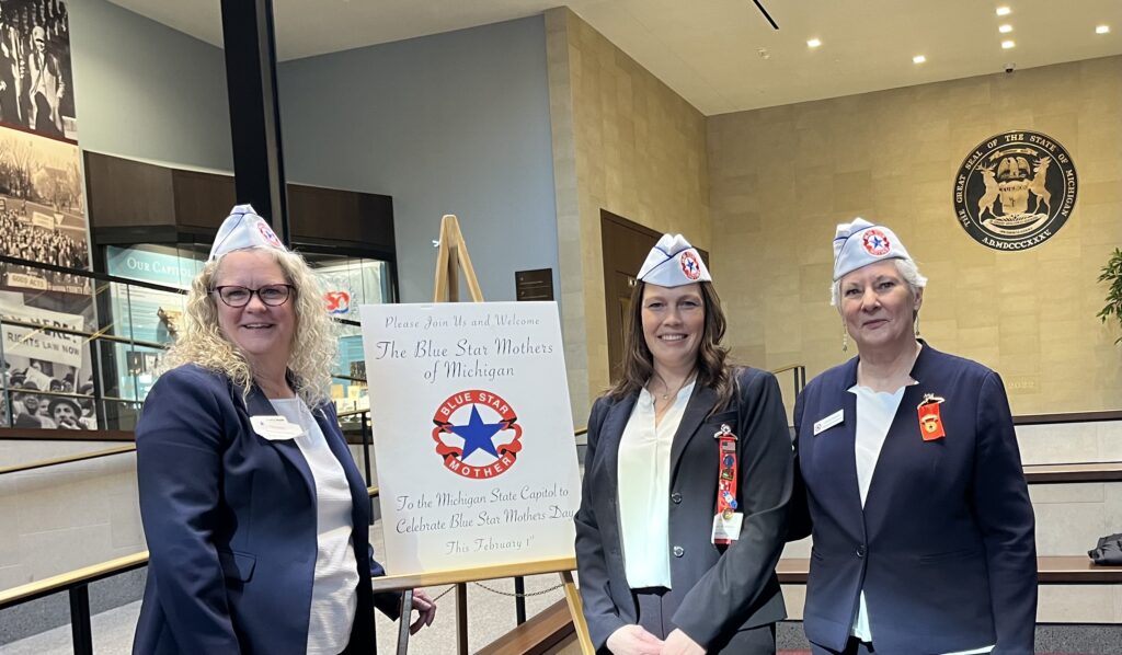 Three women standing with a sign for the Blue Star Mothers of Michigan