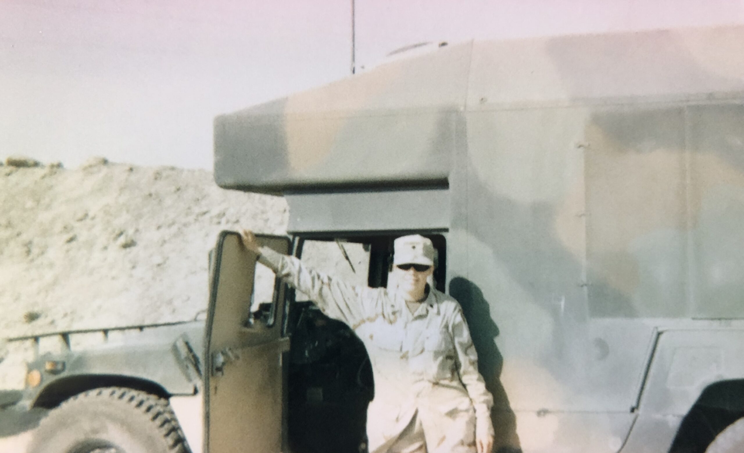 Female U.S. Army soldier in uniform standing next to a desert convoy ambulance