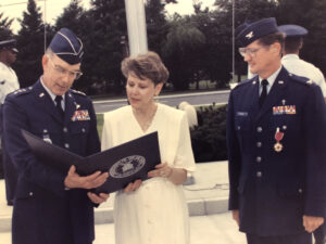 Two male Air Force Officers at a retirement ceremony standing with the wife of one officer