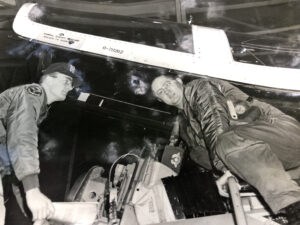 Two Air Force personnel climbing into an airplane cockpit