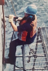 Navy sailor working over the side of a ship