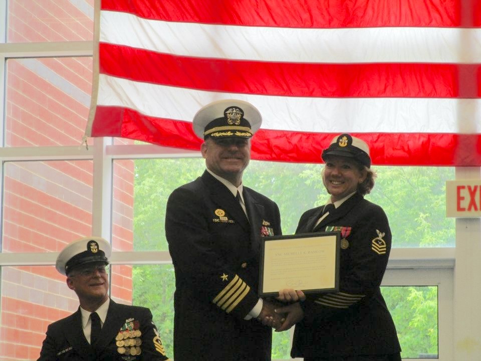 A male Navy officer presenting a certificate to a female Navy chief petty officer