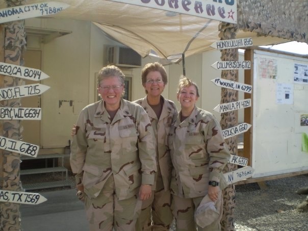 Three female Navy servicemembers standing in between arrows showing distances to various cities