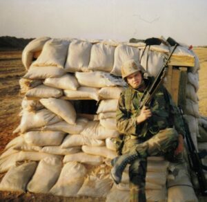 U.S. Army soldier with a military rifle sitting on a sandbag bunker