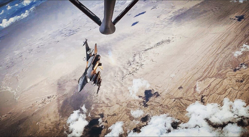 An F-16 flying over desert terrain