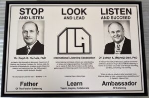A black and white placard for the International Listening Association featuring the photos of two men and describing the association