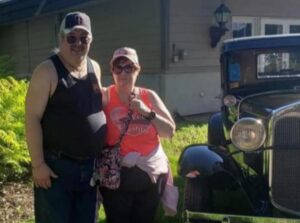 Husband and wife standing next to an antique car