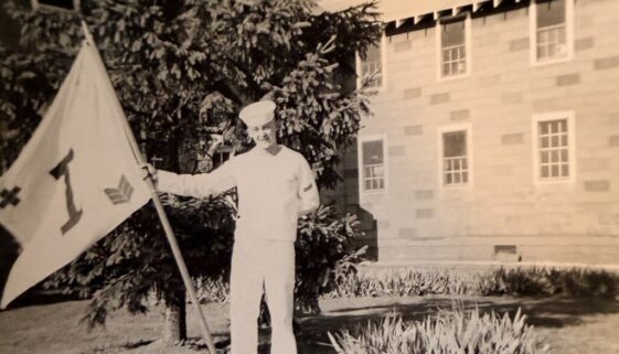 Sailor in uniform at boot camp holding company flag