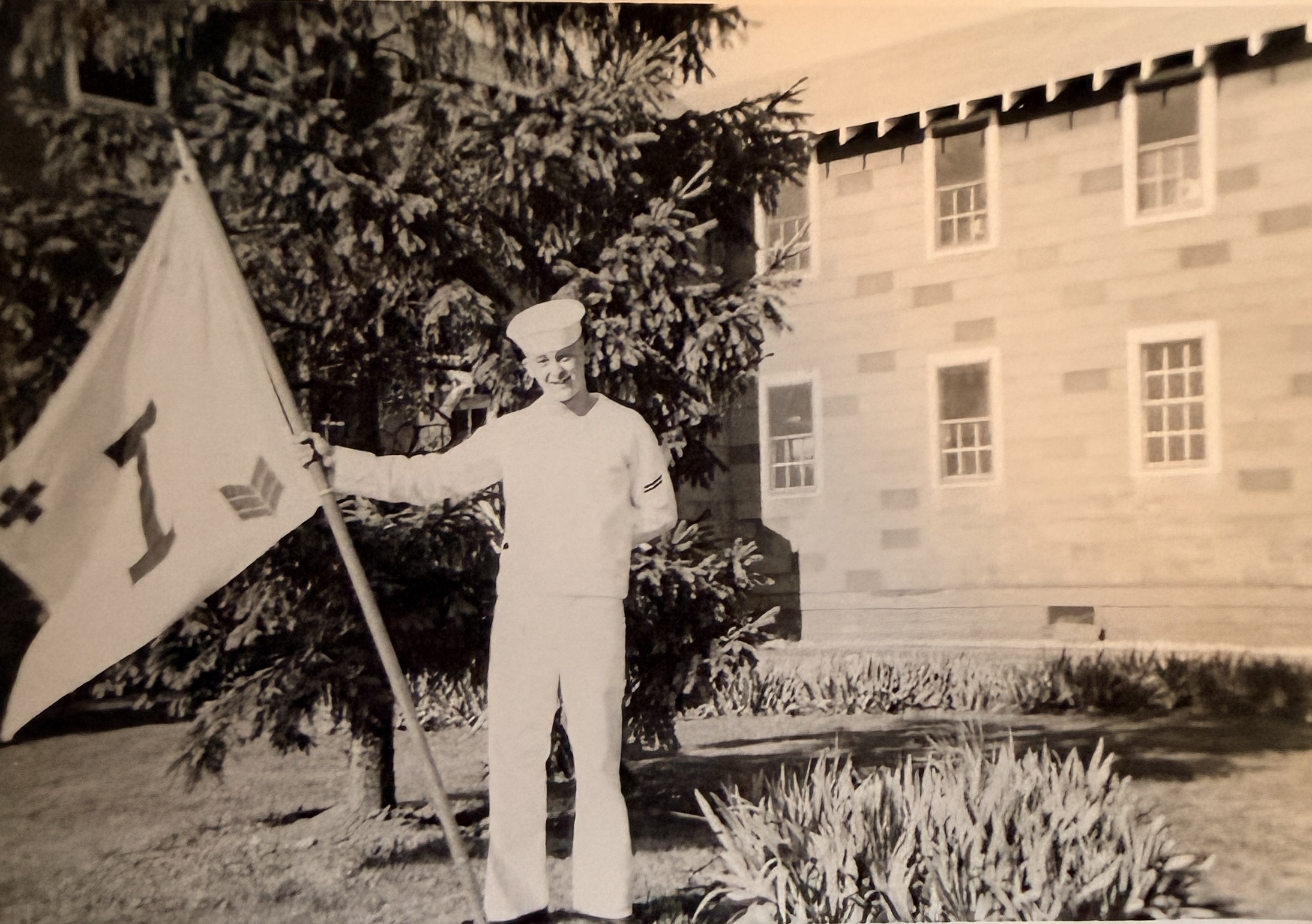 Sailor in uniform at boot camp holding company flag