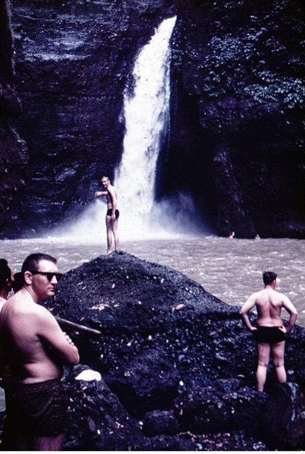 Men in bathing suits across the water from water falls