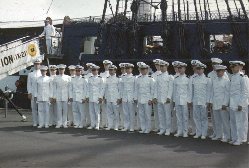 Group of new Navy ensigns standing in front of the USS Constitution