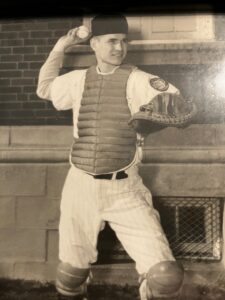 Male baseball catcher in his baseball uniform and catching gear getting ready to throw a baseball