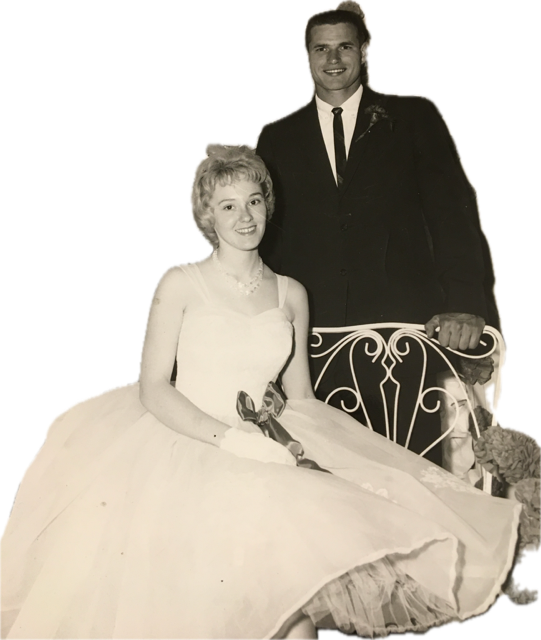 Young man in a suit standing behind a young women in a formal dress for a dance